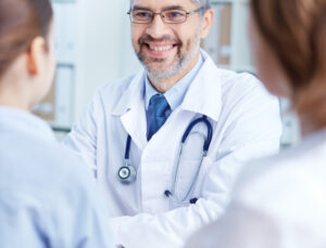 A smiling doctor wearing a stethoscope discusses health and wellness education with a community member at the Doc Talks lecture series.